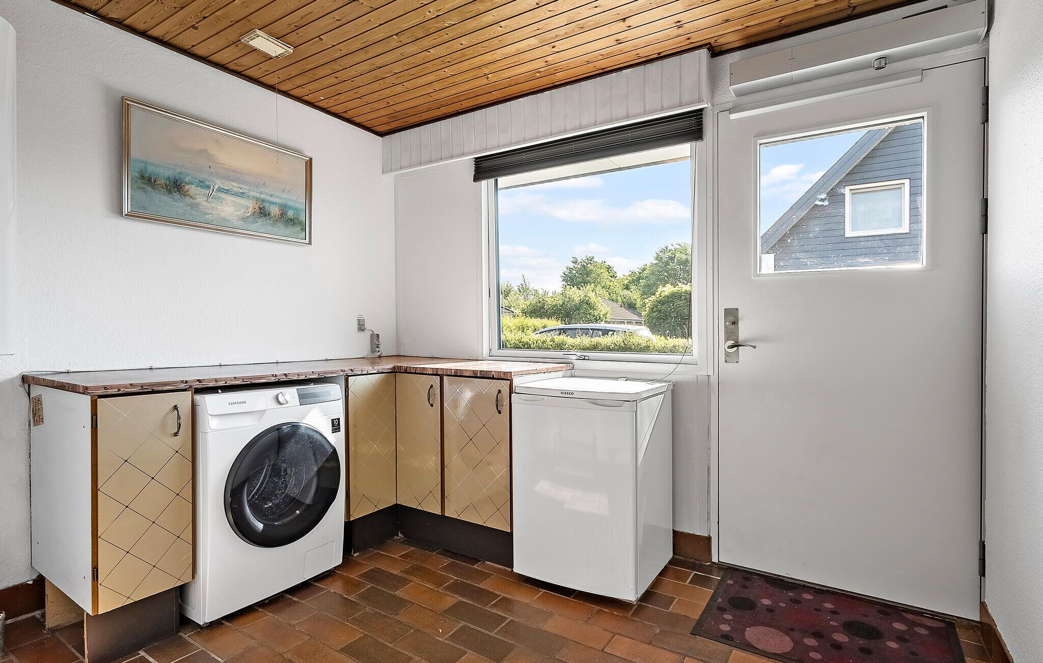 Une petite buanderie équipée d’un lave-linge, d’un sèche-linge et d’une petite fenêtre donnant sur l’extérieur.