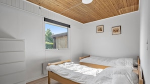 Ein Schlafzimmer mit Holzboden, einem Fenster mit Jalousien, einem Bett und einem Kleiderschrank.