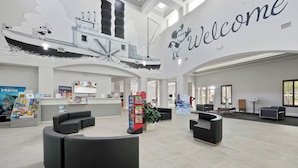 A spacious lobby with a 'Welcome' sign, seating areas, and a large ship mural on the wall. - Disney Favorite FREE Shuttle (Orlando)