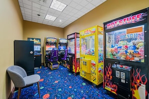 A row of arcade machines with a plush toy-filled claw machine labeled "HOT STUFF" and a "TOY TAXI" machine. - Disney Favorite FREE Shuttle (Orlando)
