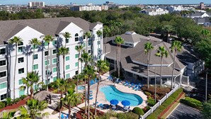 A hotel with a swimming pool, palm trees, and a view of the city. - Disney Favorite FREE Shuttle (Orlando)