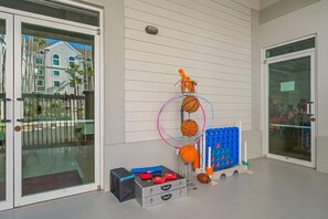 A glass door entrance with a metal gate, a basketball hoop, and a blue storage unit with orange basketballs.