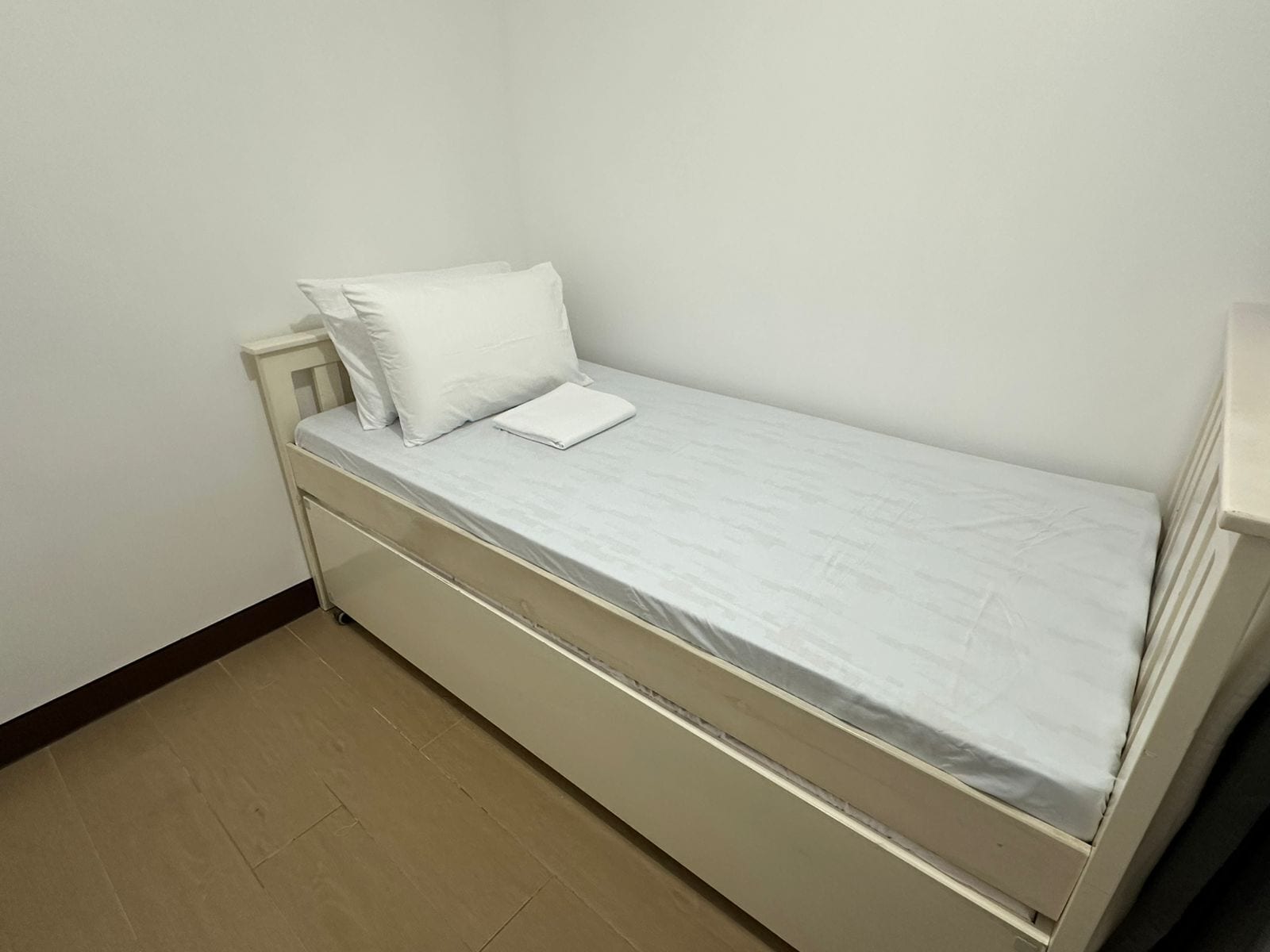 A small, single-bed room with a white mattress, a pillow, and a folded blanket.