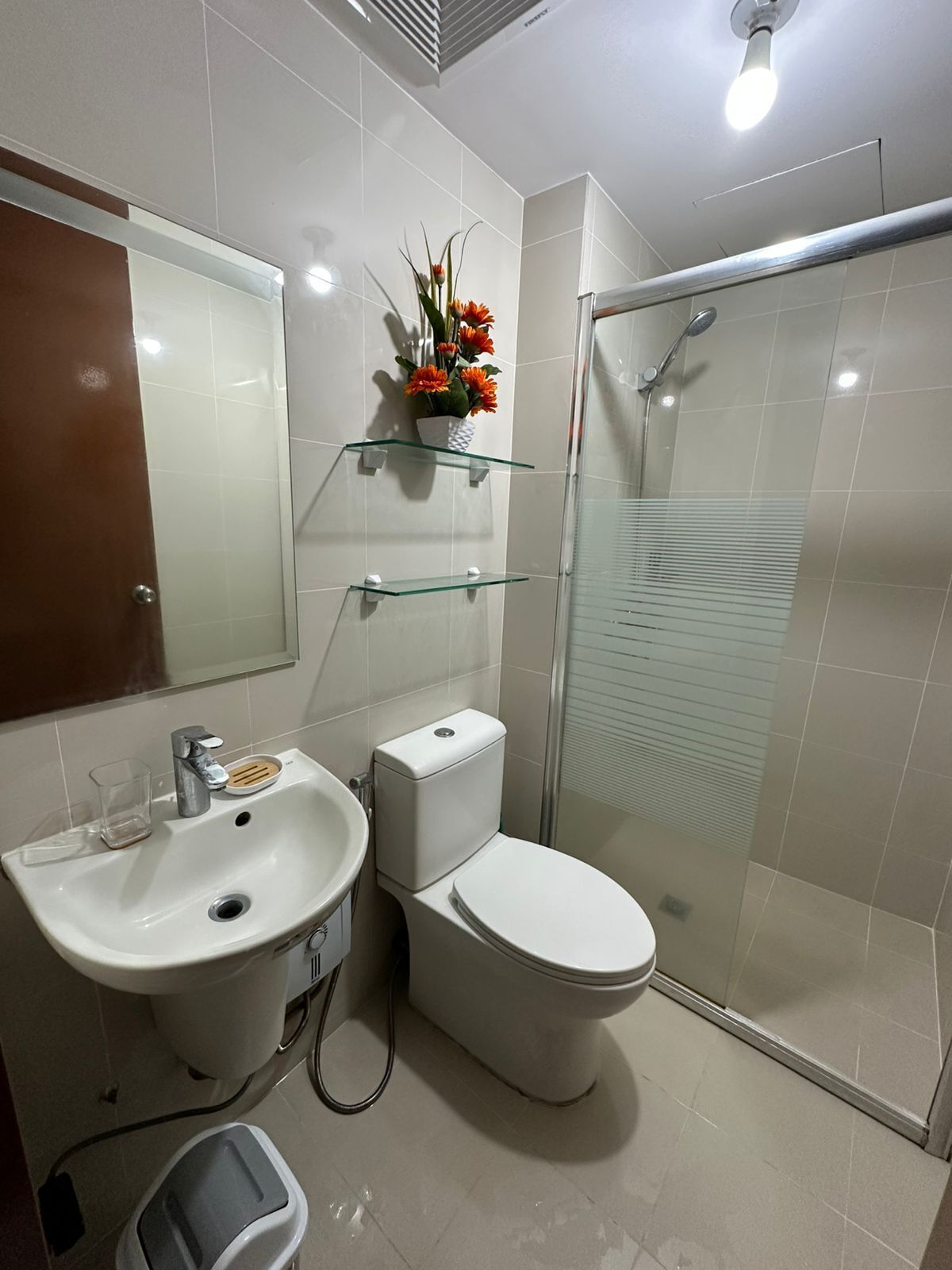 Een moderne badkamer met wastafel, toilet en douchecabine met glazen wanden.