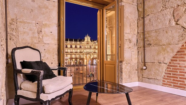 Una habitación con vistas a un edificio histórico de noche, una silla y una mesita.