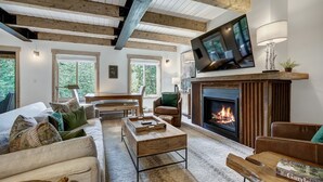 A cozy living room with a fireplace, wooden beams, a television, and comfortable seating.