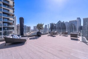 A rooftop terrace with modern furniture, a large potted plant, and a view of the city skyline.