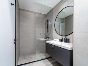 A modern bathroom with a glass-enclosed shower, a white sink with black fixtures, and a large mirror.