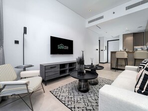 Een moderne woonkamer met een flatscreen televisie, een eethoek met een bar, en een keuken op de achtergrond.
