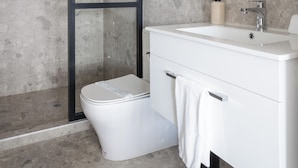 A modern bathroom with a glass-enclosed shower, a white sink, and a large mirror. - City Centre Apartment on Hanover - Studio 1 (Dunedin)