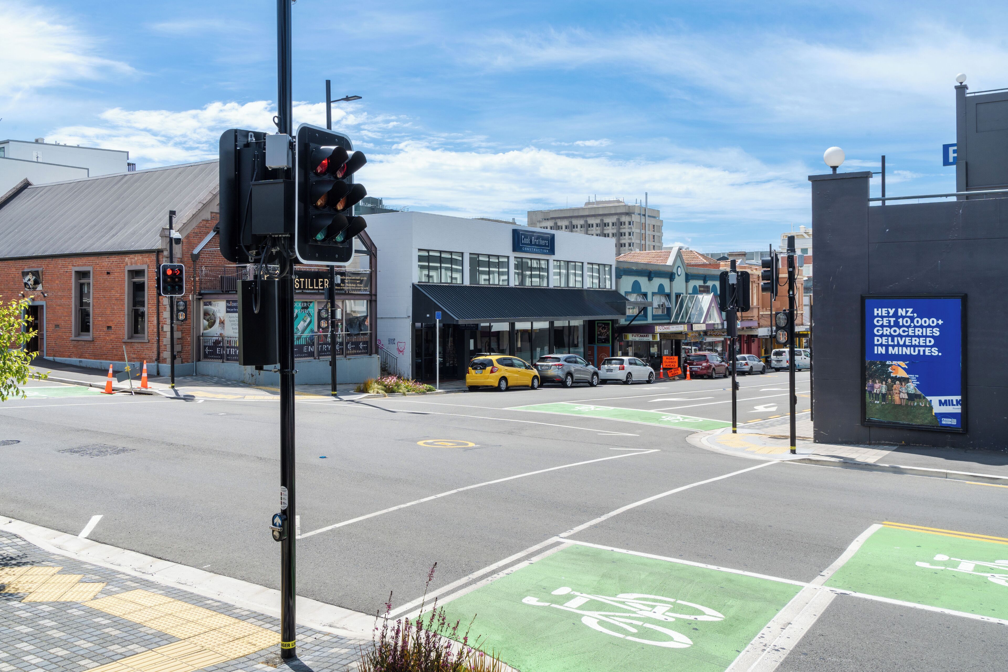 A street intersection with traffic lights, a green bike lane, and a building with a sign that reads "Stiller."