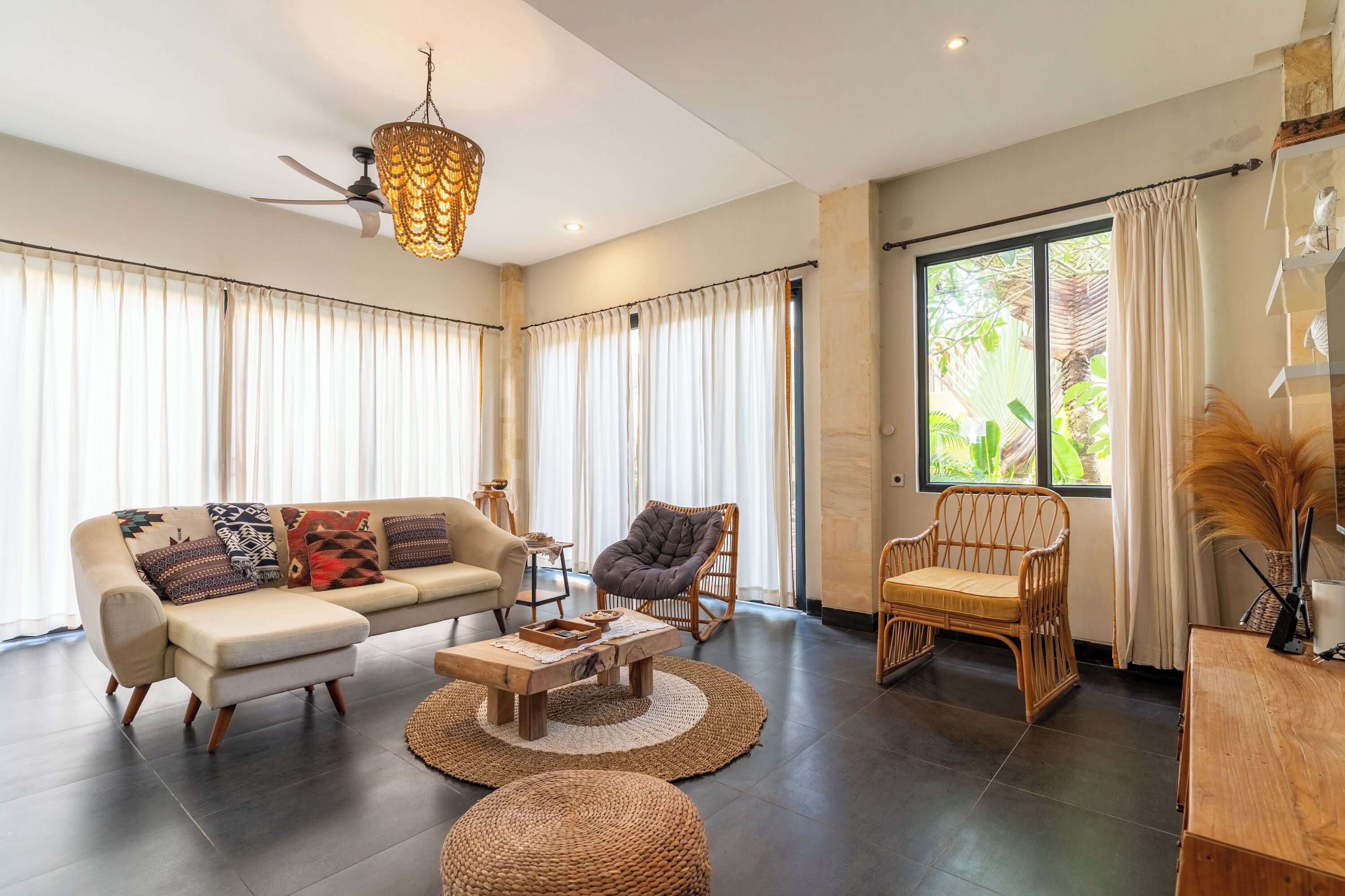 A spacious living room with a sofa, chairs, a coffee table, and a large window with curtains.