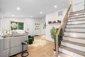 A modern living room with a grey sofa, a coffee table, and a staircase with wooden steps. - #37 - Luxury Collection (Stratford)