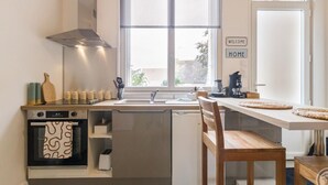 Une cuisine compacte dotée d’un four encastré, d’un lave-vaisselle et d’une fenêtre offrant une belle vue.