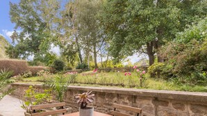 Une terrasse extérieure avec un mur en pierre, une table en bois et des bancs.