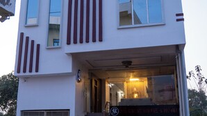 A modern two-story building with a flat roof, large windows, and a visible entrance with steps leading up to it. - SR GUEST HOUSE  (Agra)
