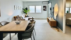 Ein modernes Wohnzimmer mit Essbereich, großen Fenstern und Blick auf die Stadt.