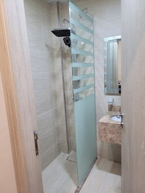 A bathroom with a glass shower enclosure, a sink with a marble countertop, and a mirror above the sink. - Qurtoba Al Aziziah (Makkah)
