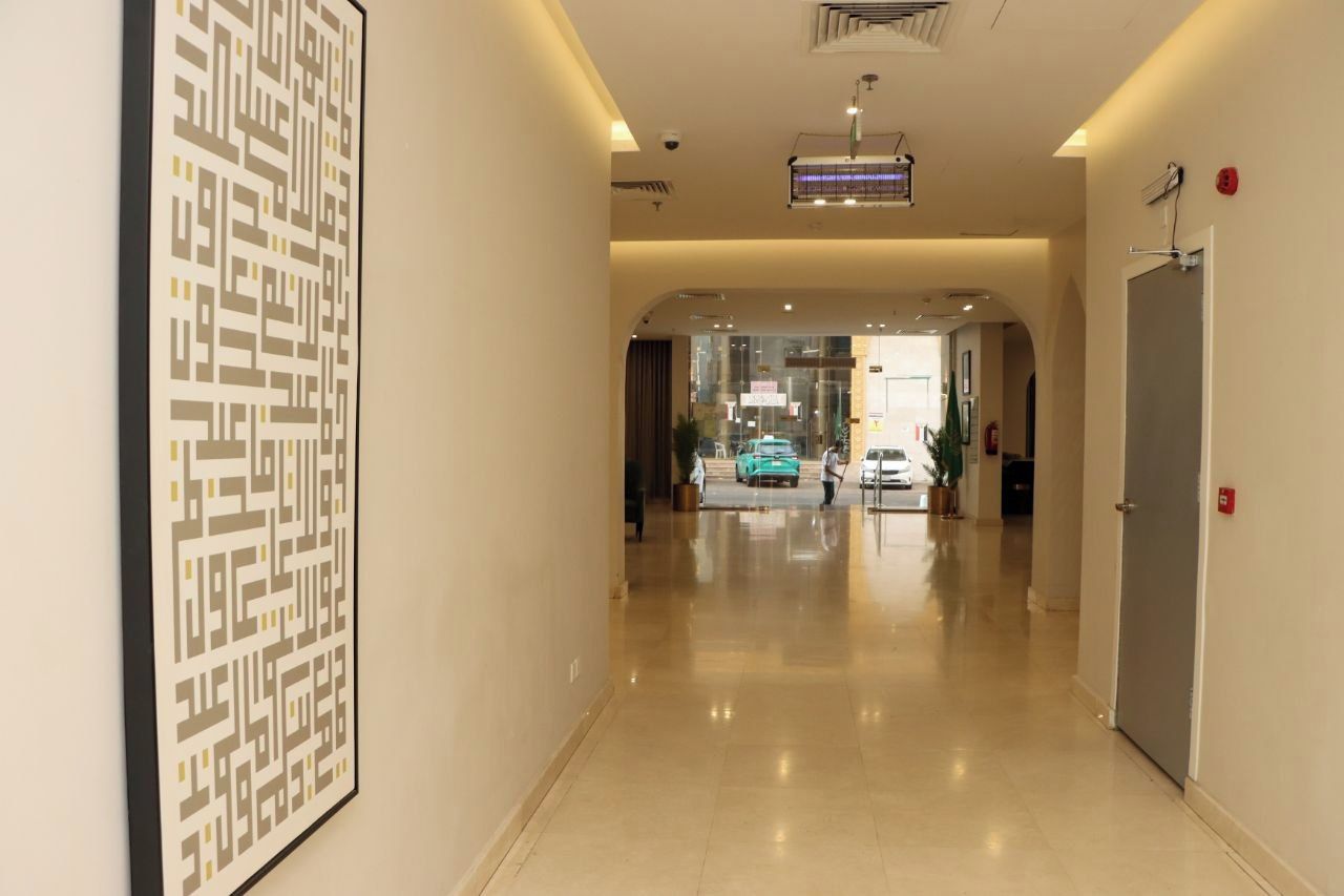 Un pasillo de hotel con diseño moderno, una obra de arte abstracta enmarcada en la pared y un coche estacionado fuera.