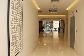 A hotel corridor with a modern design, a framed abstract artwork on the wall, and a car parked outside. - Qurtoba Al Aziziah (Makkah)
