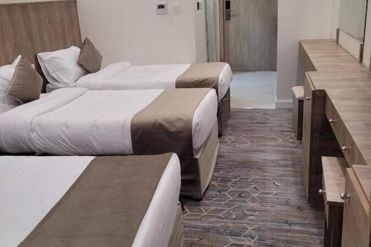 Habitación de hotel con dos camas, cabecero de madera, escritorio y suelo estampado.