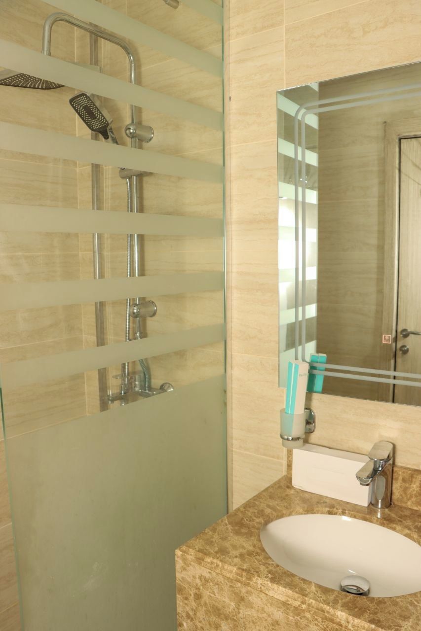 A bathroom with a glass shower enclosure, a sink, and a mirror.