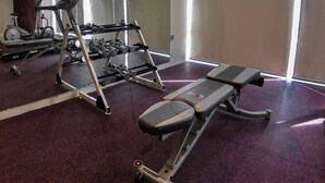 Ein Fitnessraum mit Trainingsgeräten, einer Bank und einem Spiegel.