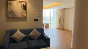 Ein modernes Wohnzimmer mit einem blauen Sofa, einem Holztisch und einem großen Fenster mit Blick auf die Stadt.