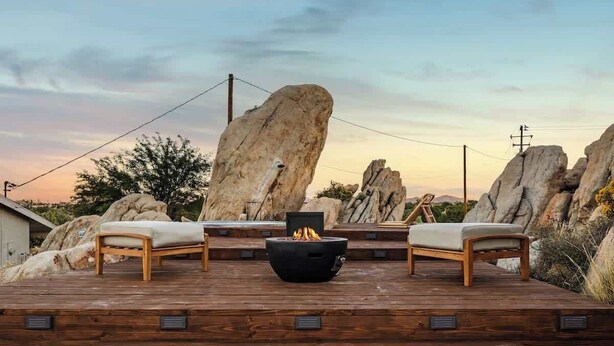 A wooden deck with two lounge chairs and a black fire pit in the center. - Bijou • Romantic Sanctuary, Hot Tub in Boulders (Yucca Valley)