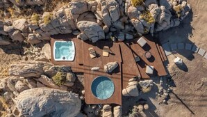 An outdoor hot tub and seating area surrounded by rocks. - Bijou • Romantic Sanctuary, Hot Tub in Boulders (Yucca Valley)