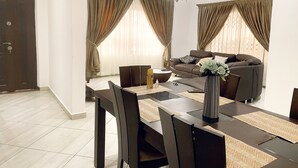 Una sala de estar moderna con un sofá, una mesa de comedor con sillas y una araña.