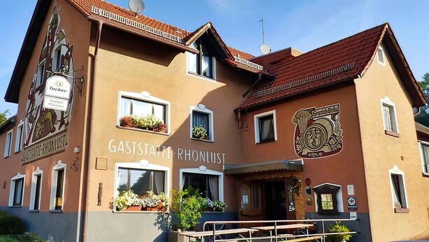 A building with the sign "GASTSTÄTTE RONLUST" and a coat of arms.