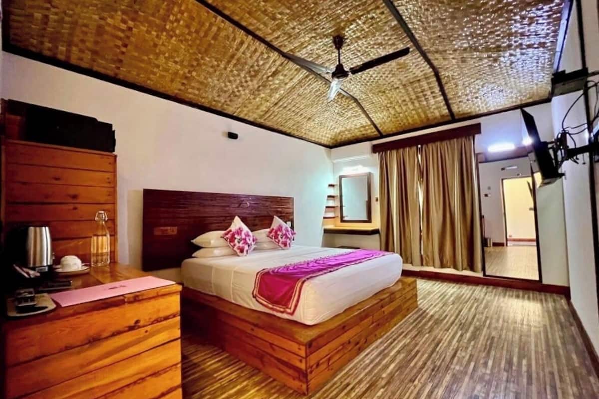 A room with a wooden bed, a wooden dresser, a ceiling fan, and a view of a door.