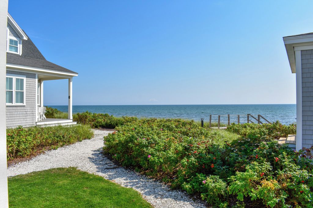 A coastal property with a gravel path leading to a wooden deck overlooking the sea.