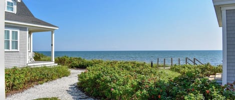 A coastal property with a gravel path leading to a wooden deck overlooking the sea.