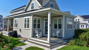 A two-story house with a covered porch, white siding, and a small garden.