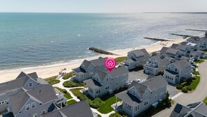 A coastal residential area with houses, a beach, and a pier.