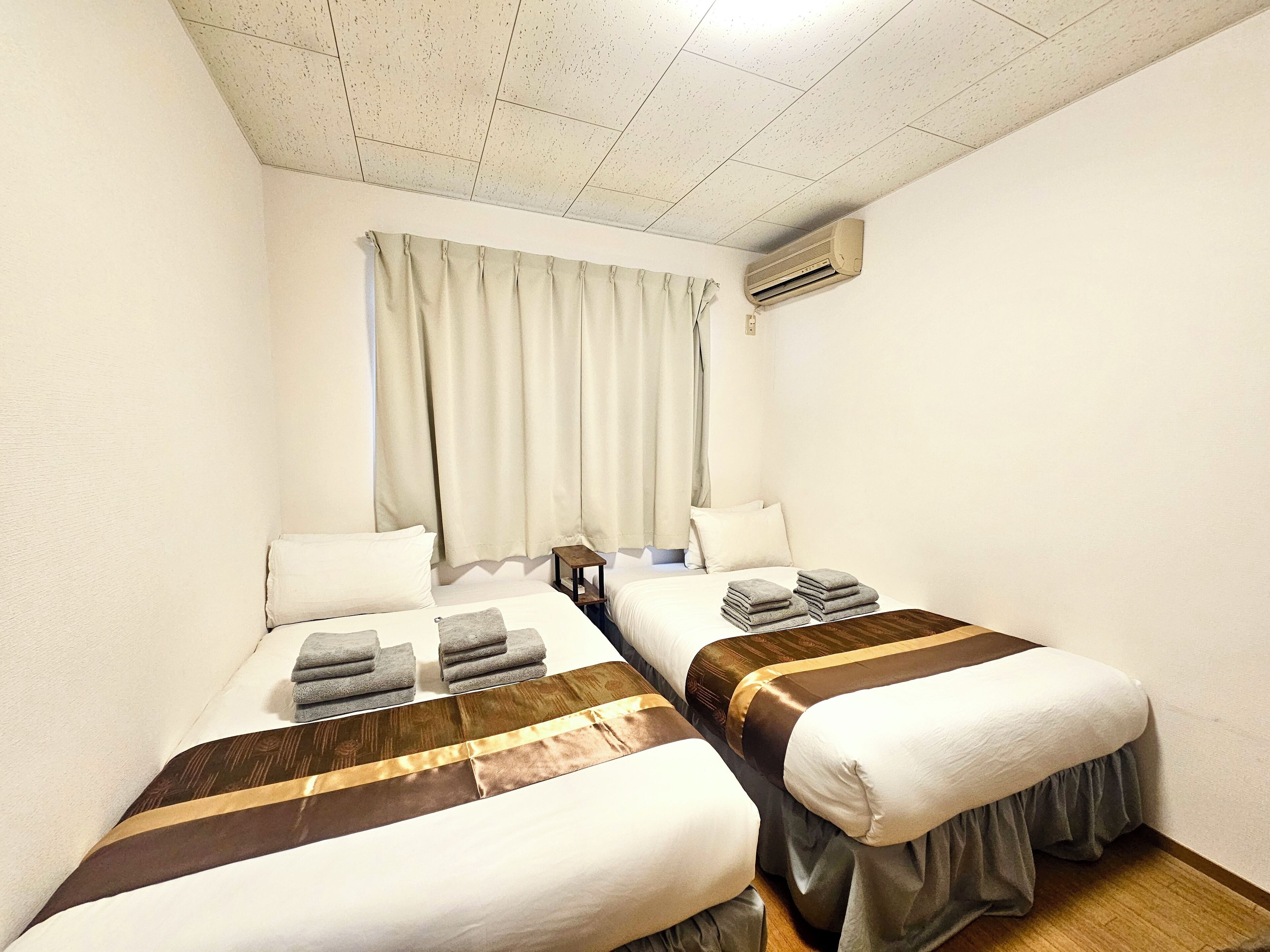 A hotel room with two beds, each with a brown and white striped bedspread, white pillows, and neatly folded towels.