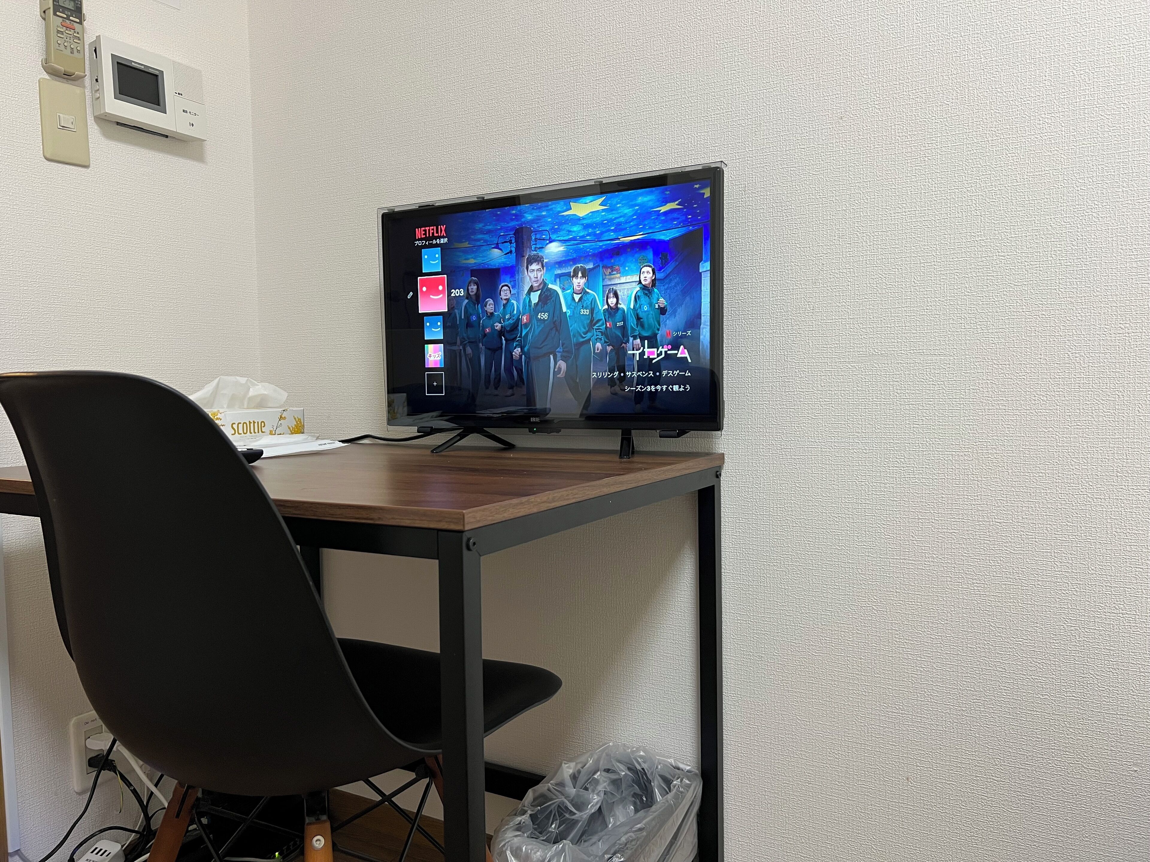 A television mounted on a wall displaying a Netflix interface with a group of people in a blue outfit.