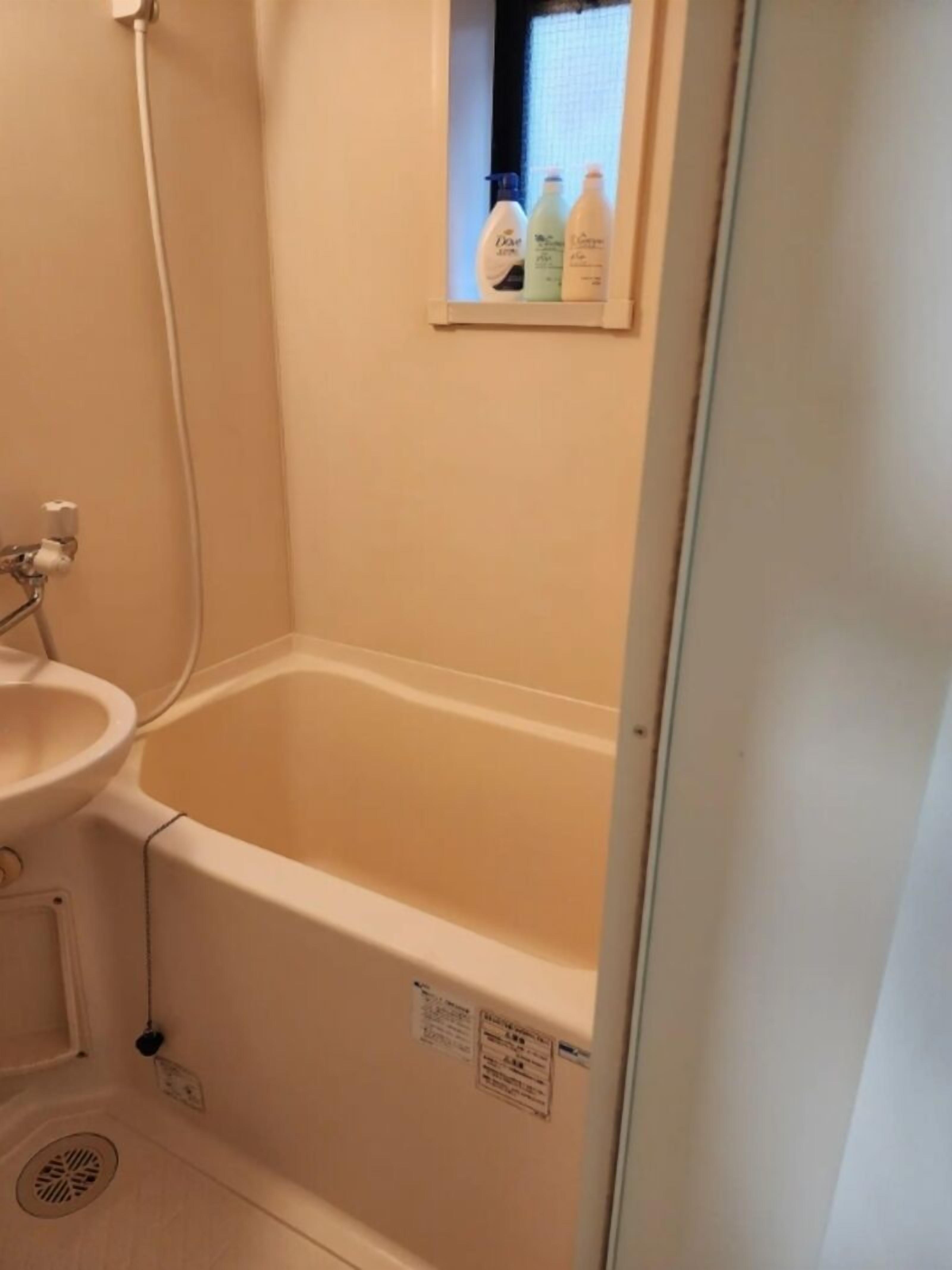 A bathroom with a bathtub, a sink, and a window with bottles.