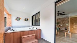 A modern bathroom with a wooden vanity, a large bathtub, and a small seating area with a table and chairs. - Centrally located condo with private plunge pool (Huatulco)