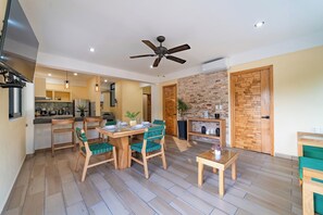 A spacious living area with a dining table, chairs, a ceiling fan, and a kitchen in the background. - Centrally located condo with private plunge pool (Huatulco)