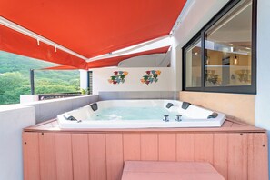 A hot tub with a wooden deck, a red canopy, and a view of greenery. - Centrally located condo with private plunge pool (Huatulco)
