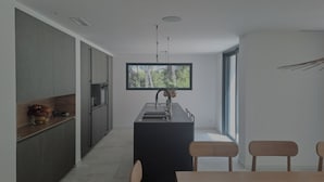 Cozinha moderna com ilha central, armários escuros e uma janela grande que proporciona luz natural.