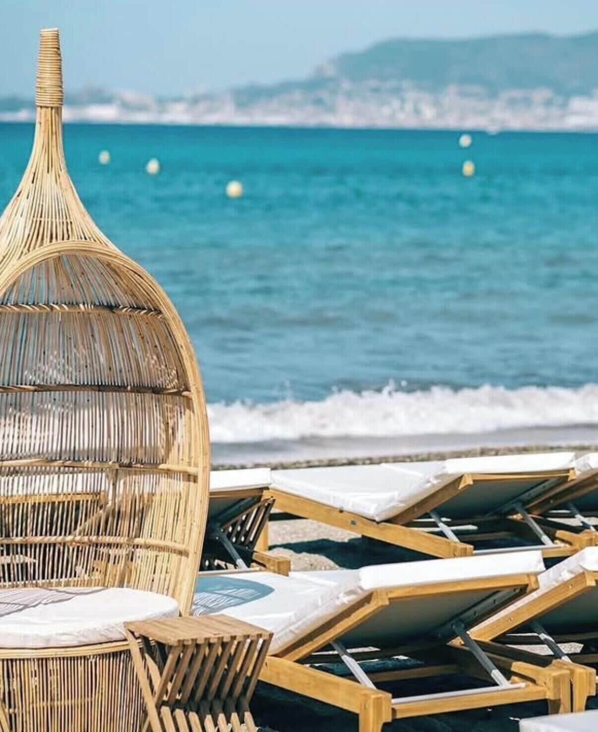 Un área de descanso en la playa con tumbonas y un parasol tejido.