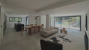 Uma sala de estar espaçosa com uma grande janela, área de jantar e cozinha.