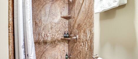A bathroom with a shower, marble walls, and a towel rack.