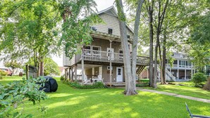 Ein zweistöckiges Haus mit Veranda, überdachter Terrasse und Rasen.