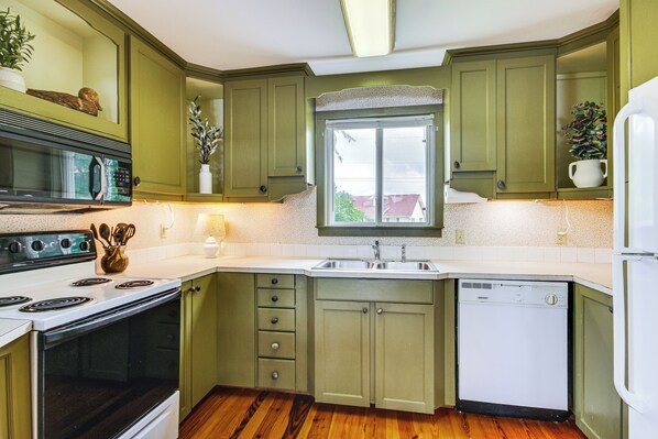 A kitchen with green cabinets, a microwave, stove, sink, and dishwasher. - Private Boat Dock: Waterfront Lake Murray Haven (Prosperity)