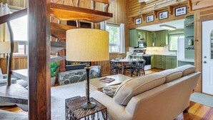 Ein gemütliches Blockhaus-Interieur mit einer Holztreppe, einem Essbereich und einem Wohnzimmer mit Sofa und Lampe.